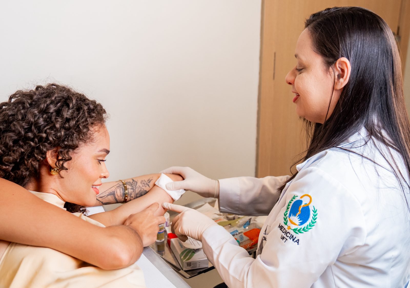 Ginecologista da CLAF conversando e sorrindo com paciente durante avaliação do braço